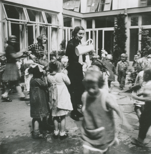 876959 Afbeelding van een groep kleuters die spelen op de binnenplaats van de RK kleuterschool (fröbelschool, ...